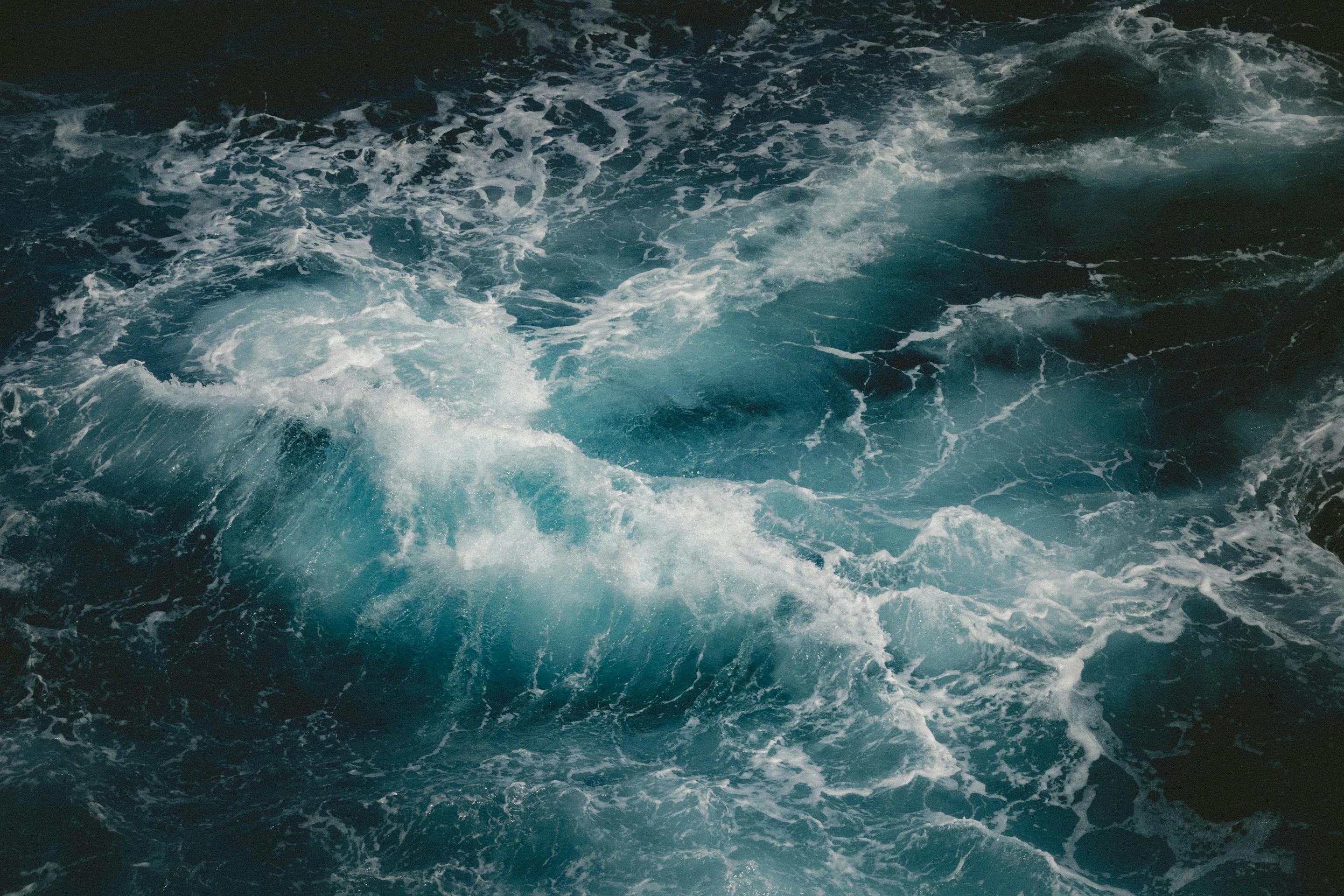 A turbulent blue ocean wave with white foam